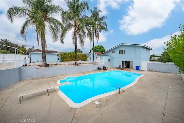 front view of house with a yard and palm trees