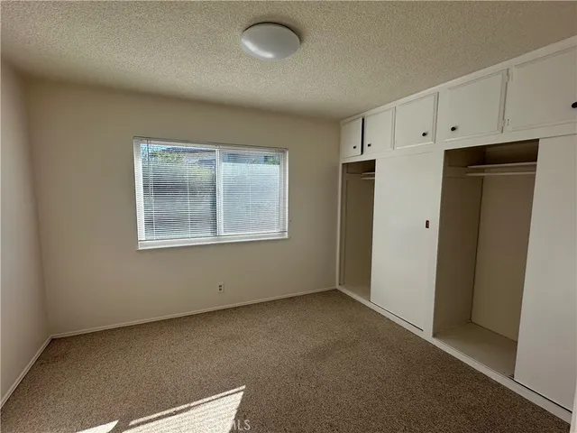 a view of an empty room with closet and a window