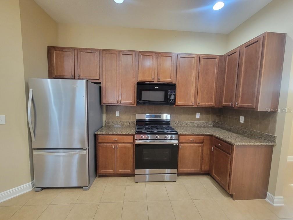 10418 Fenceline Road New Port Richey, FL 34655 - Photo 13 of 36 a kitchen with stainless steel appliances granite countertop a refrigerator stove a sink and dishwasher