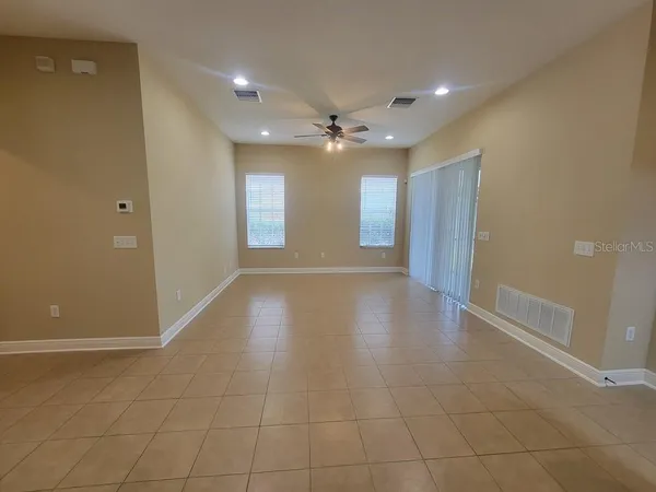 a view of an empty room with glass door and chandelier fan