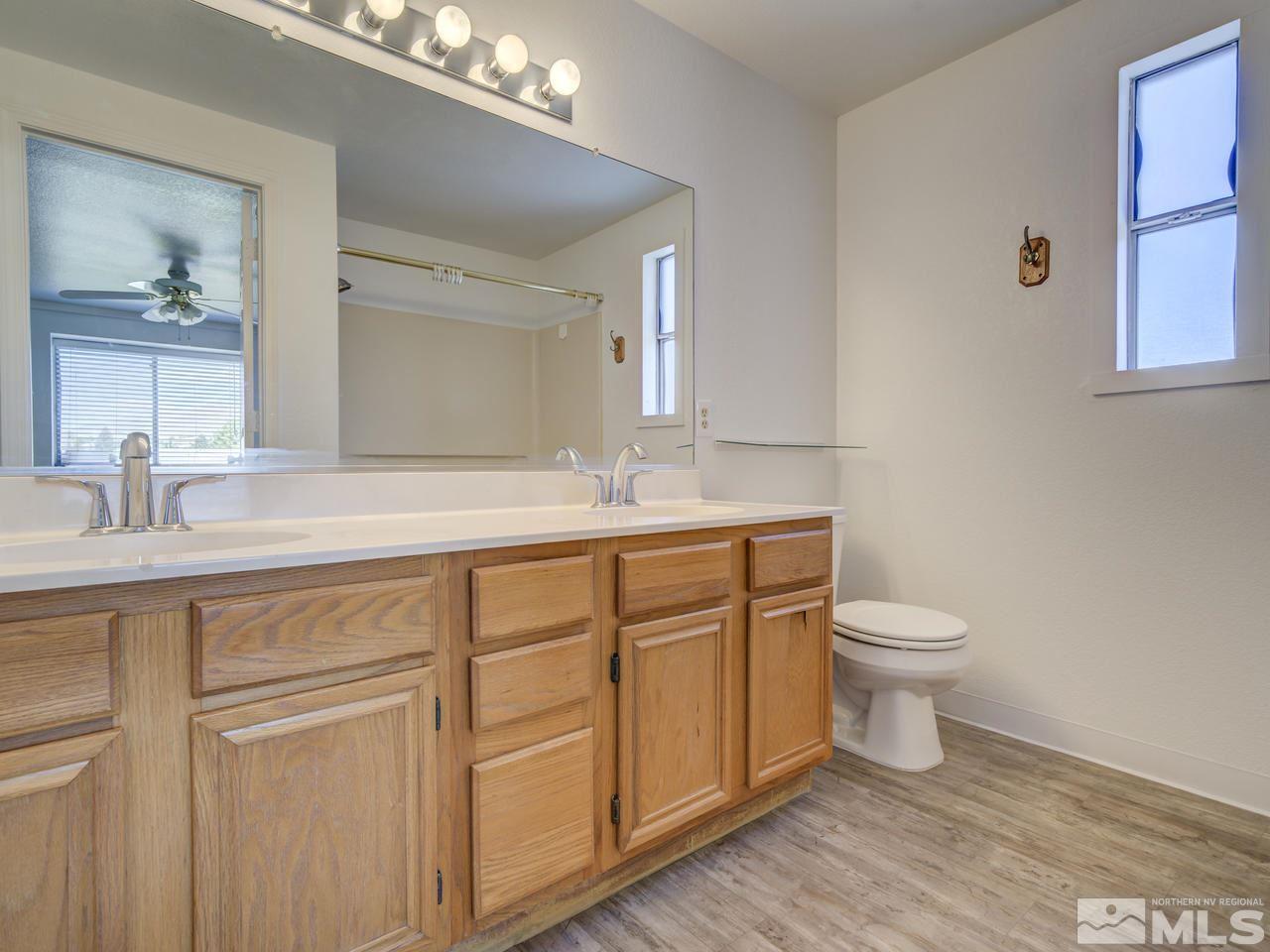 17175 Waxwing Street Reno, NV 89508 - Photo 19 of 25 a bathroom with a granite countertop sink a toilet and a mirror