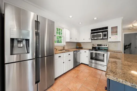 a kitchen with stainless steel appliances granite countertop a refrigerator a stove a sink and a microwave