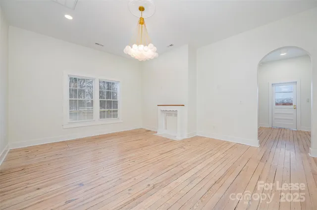 a view of empty room with wooden floor and window