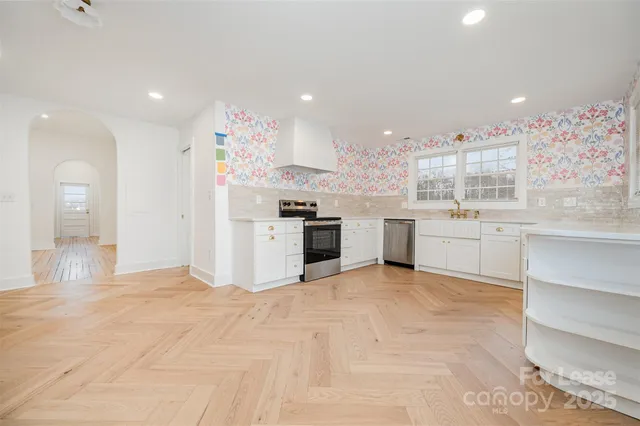 a large white kitchen with a stove top oven and kitchen island