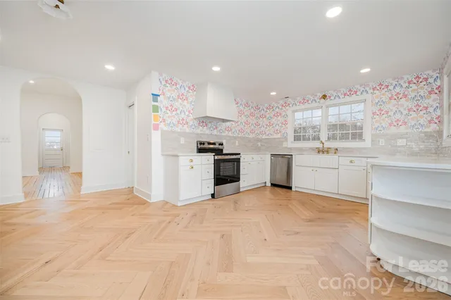 a large white kitchen with a stove top oven and kitchen island