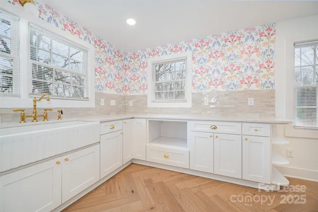 a white kitchen with cabinets a sink and a window
