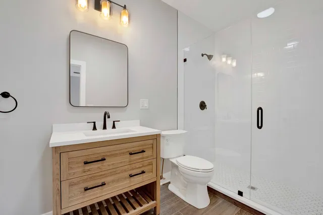 a bathroom with a toilet a sink a mirror and shower