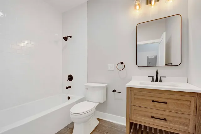 a bathroom with a toilet a sink a mirror a bathtub and vanity