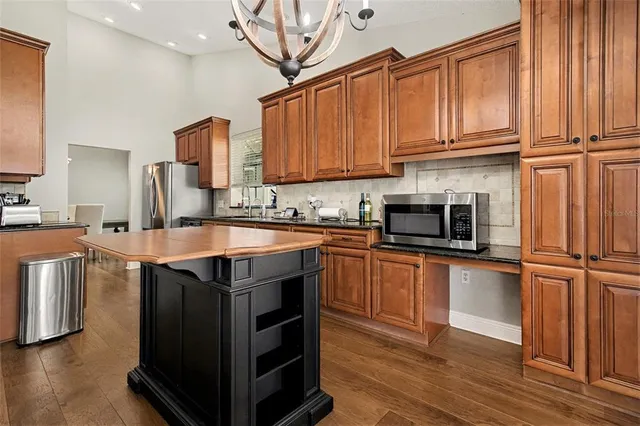 a kitchen with stainless steel appliances granite countertop a stove a sink dishwasher and a microwave oven with wooden floor
