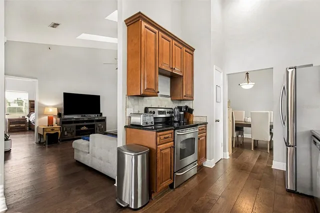a living room with stainless steel appliances furniture a flat screen tv and a refrigerator