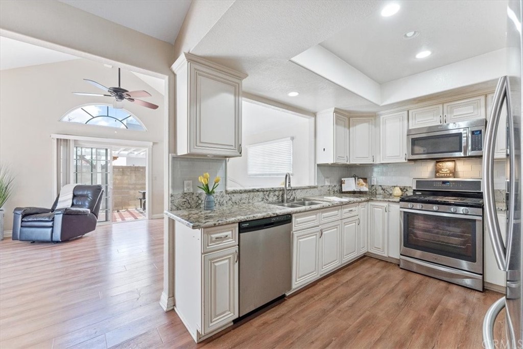 1013 London Circle Placentia, CA 92870 - Photo 19 of 45 a kitchen with stainless steel appliances granite countertop hardwood floor sink stove and white cabinets