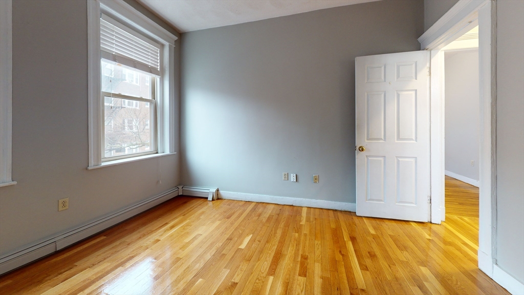 1625 Commonwealth Avenue, Unit 9 Boston, MA 02135 - Photo 5 of 8 a view of an empty room with wooden floor and a window