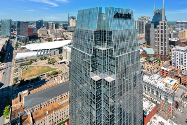a bedroom with a bed a dresser and potted plants with wooden floor