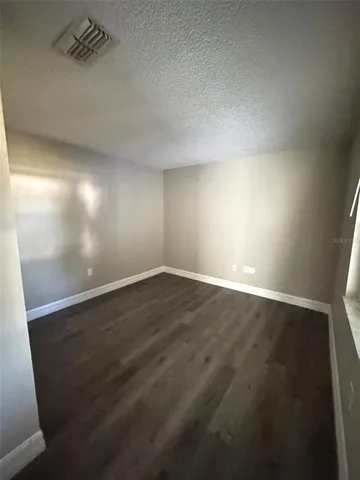 en empty room with wooden floor and windows