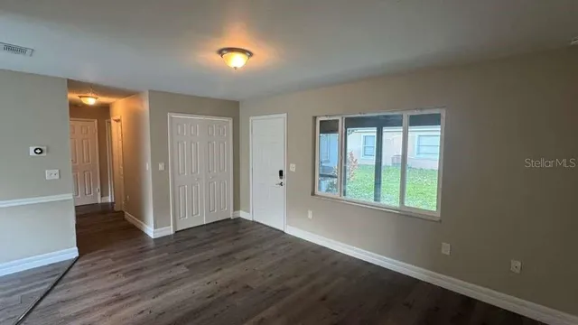 an empty room with wooden floor and windows