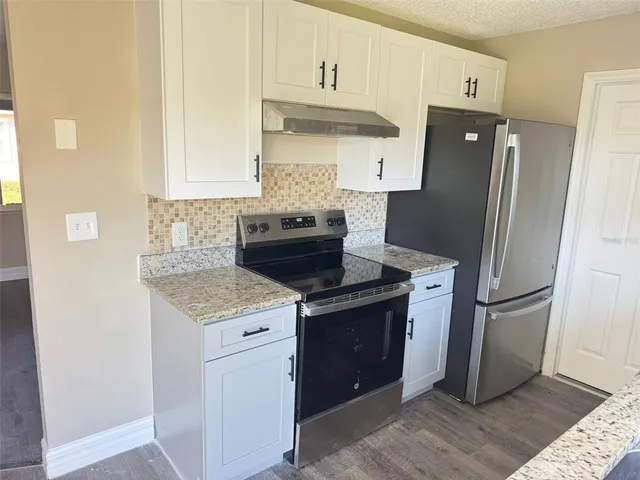 a kitchen with stainless steel appliances granite countertop a refrigerator and a stove