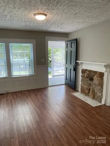 an empty room with wooden floor fireplace and windows