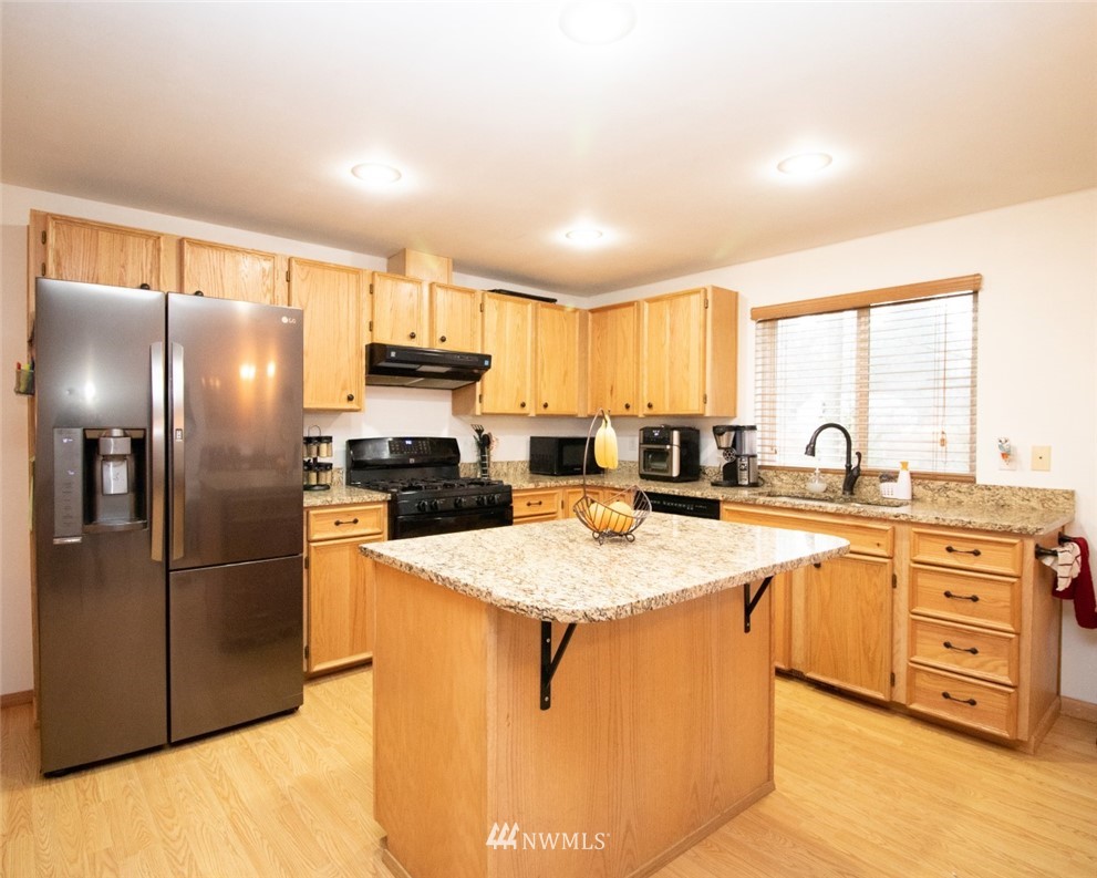 214 Fern Meadows Loop Southeast Port Orchard, WA 98366 - Photo 4 of 23 a kitchen with stainless steel appliances granite countertop a refrigerator a stove a sink and a microwave