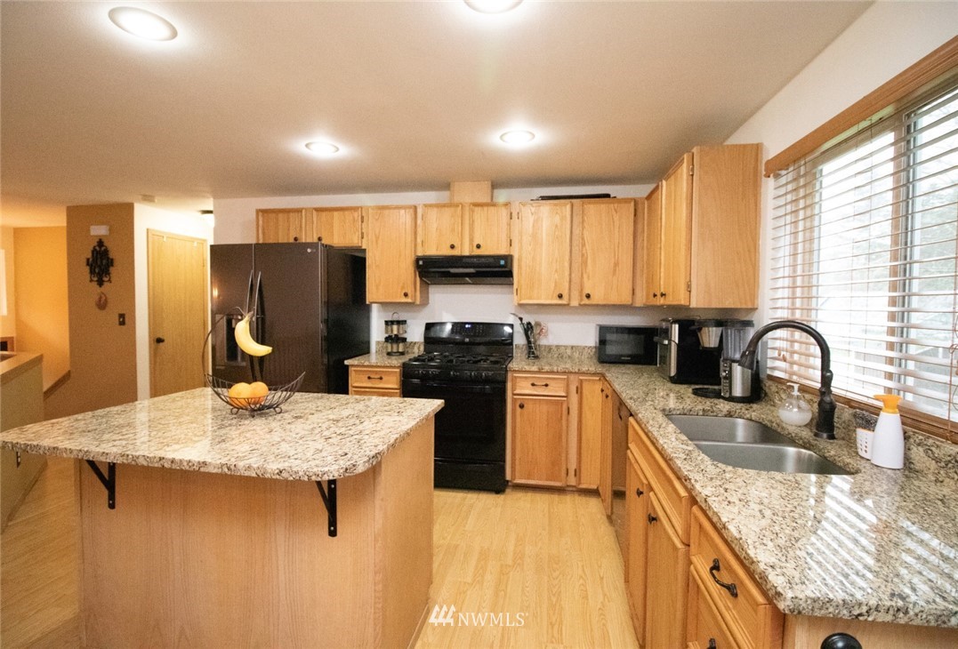 214 Fern Meadows Loop Southeast Port Orchard, WA 98366 - Photo 6 of 23 a kitchen with kitchen island granite countertop a sink stove refrigerator and cabinets