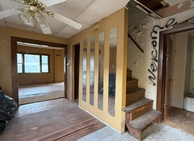a view of a hallway to a livingroom with wooden floor and furniture
