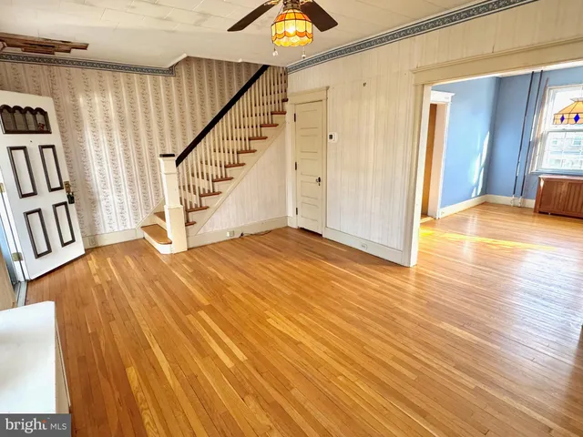 a view of an empty room with wooden floor and stairs