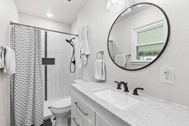 a bathroom with a granite countertop toilet a sink and a mirror
