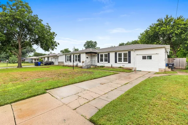 a view of house with a big yard and potted plants