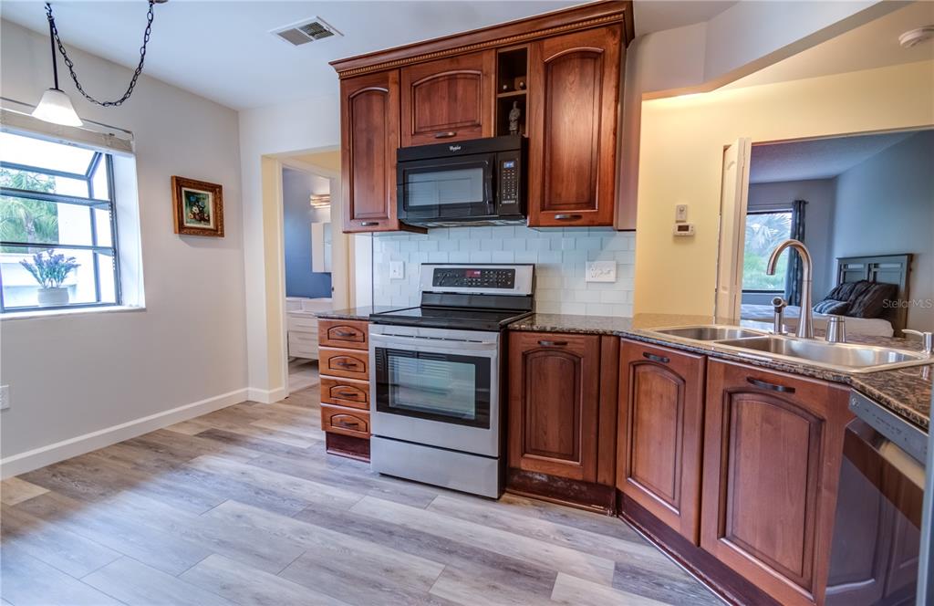 600 Carriage House Lane, Unit 201 Nokomis, FL 34275 - Photo 6 of 23 a kitchen with stainless steel appliances granite countertop a stove and a microwave