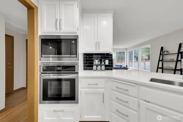 a kitchen with granite countertop white cabinets and stainless steel appliances