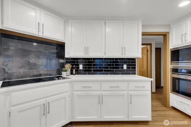 a kitchen with white cabinets and stainless steel appliances