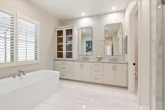 a spacious bathroom with a double vanity sink a mirror a bathtub and next to a window