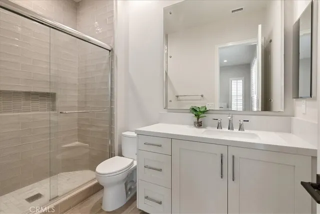 a bathroom with a toilet sink vanity granite and shower