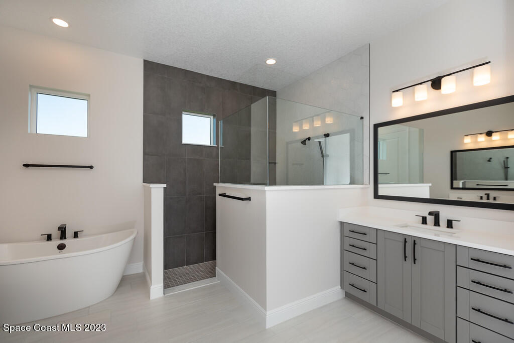 3940 Domain Court Melbourne, FL 32934 - Photo 13 of 27 a bathroom with a bathtub a double vanity sink and mirror