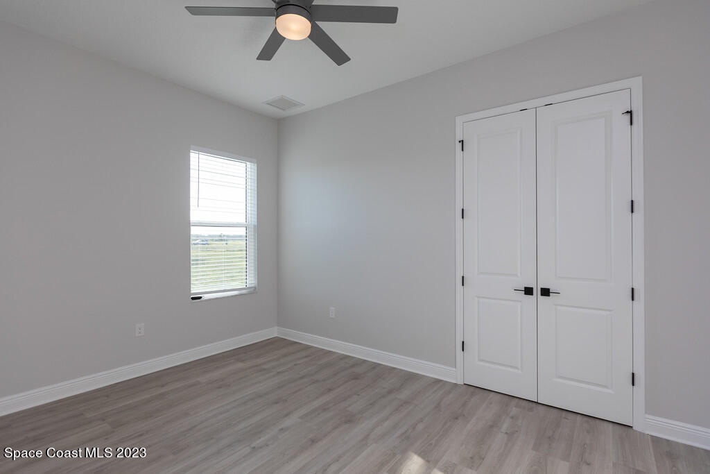 3940 Domain Court Melbourne, FL 32934 - Photo 23 of 27 an empty room with wooden floor cabinet and windows