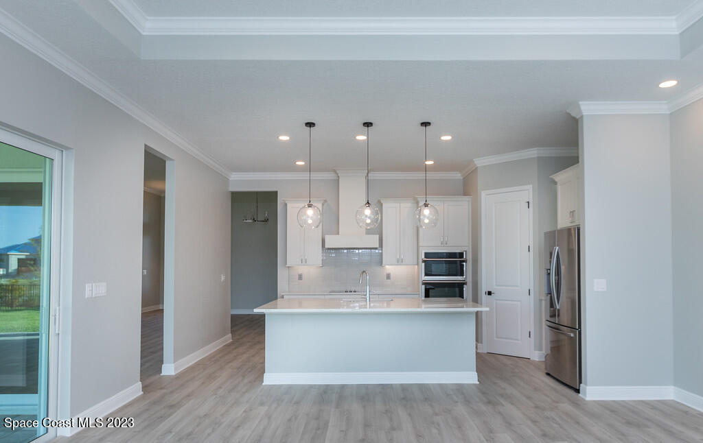 3940 Domain Court Melbourne, FL 32934 - Photo 9 of 27 a large kitchen with stainless steel appliances kitchen island a large counter top and a refrigerator