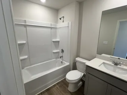 a bathroom with a bathtub shower sink vanity mirror and toilet