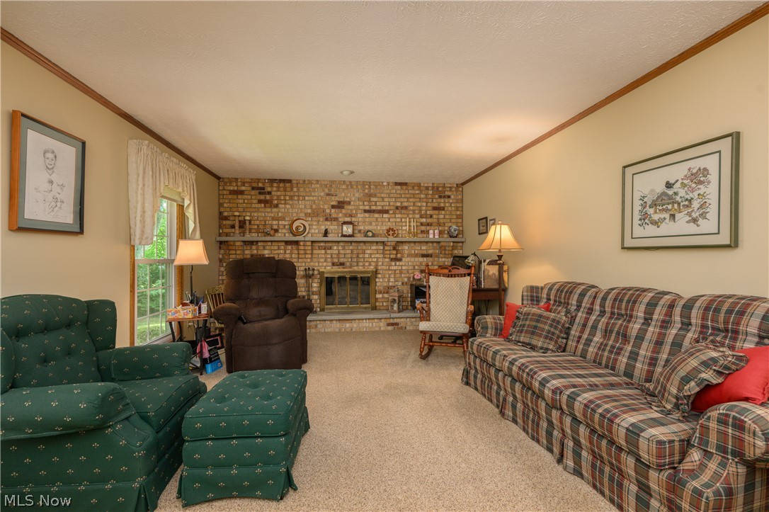 3281 Brenner Road Barberton, OH 44203 - Photo 18 of 33 Living room featuring brick wall, carpet floors, a brick fireplace, and crown molding