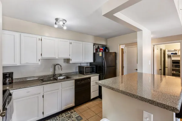 a kitchen with granite countertop a sink a refrigerator and cabinets