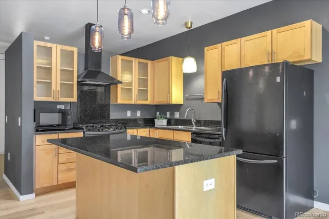 a kitchen with stainless steel appliances granite countertop a refrigerator a sink and a stove