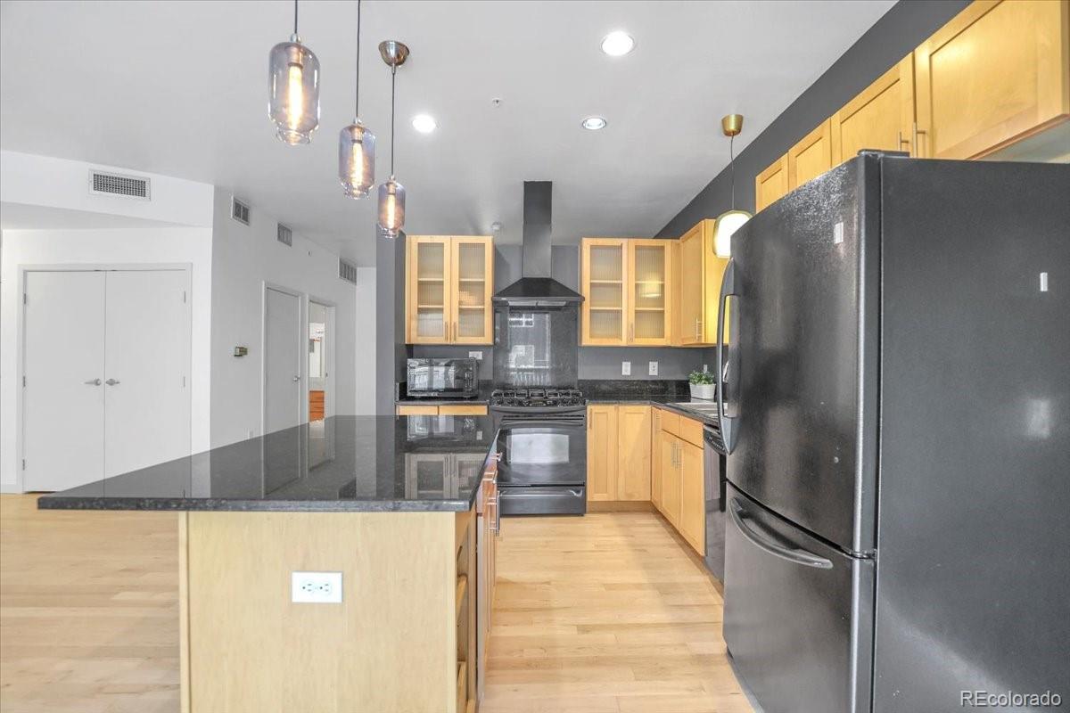 1438 Little Raven Street, Unit 201 Denver, CO 80202 - Photo 6 of 27 a kitchen with stainless steel appliances granite countertop a refrigerator a sink and a stove