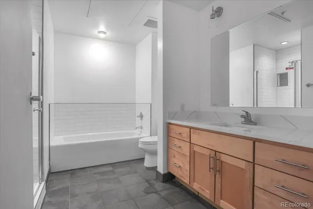 a bathroom with a granite countertop sink a toilet and bathtub
