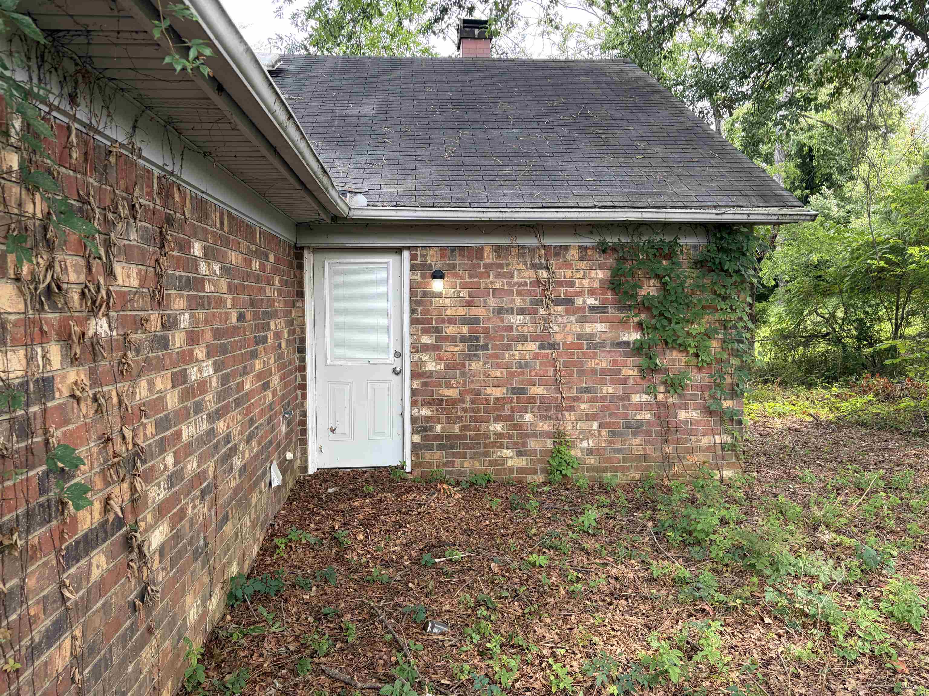 4993 Cedar View Road Memphis, TN 38118 - Photo 4 of 23 Brick exterior with a white entry door, exterior lighting, and an asphalt shingle roof