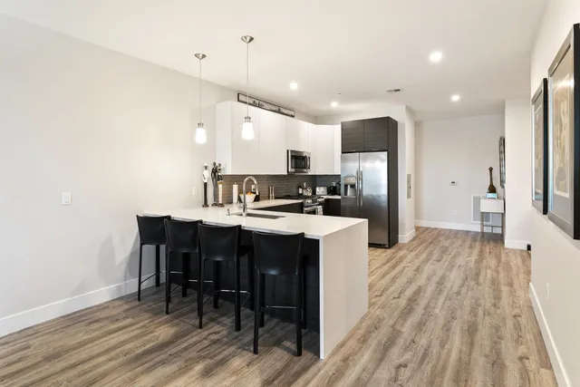 a kitchen with kitchen island wooden floors appliances and cabinets