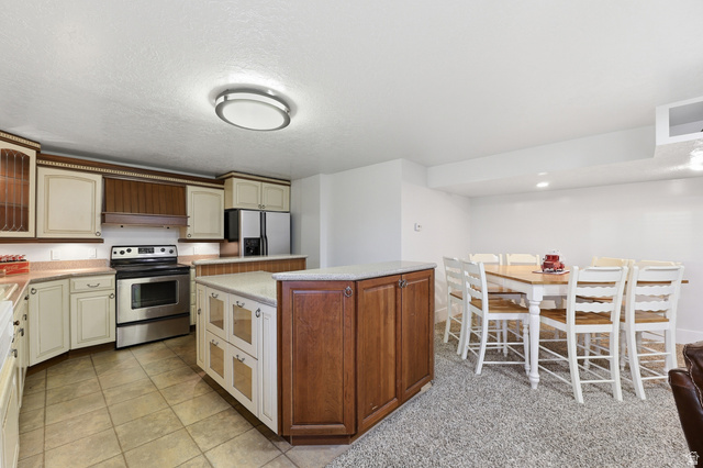 2342 Charros Road Sandy, UT 84092 - Photo 44 of 94 Kitchen area featuring a light beige tile floor, stainless steel appliances, and a central island with a light-toned countertop