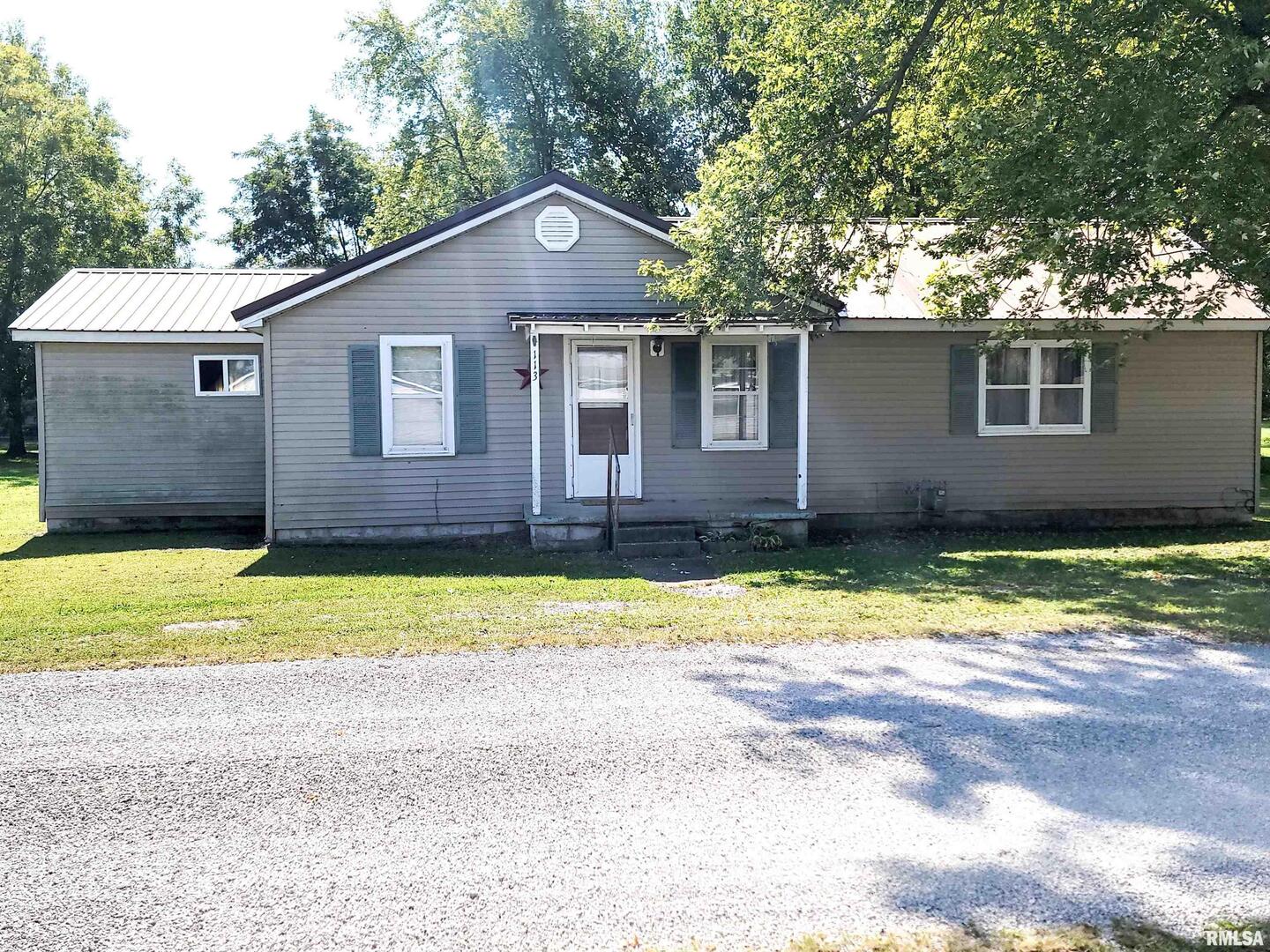 a front view of house with yard and trees in the background