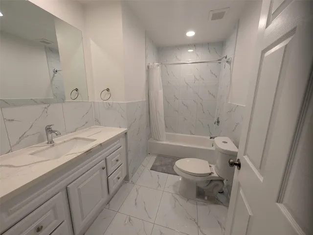 a bathroom with a granite countertop sink a toilet and a shower