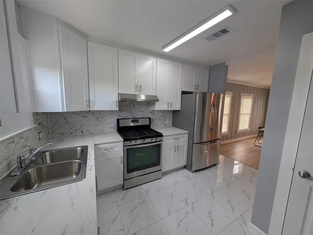 a kitchen with stainless steel appliances granite countertop a refrigerator sink and stove