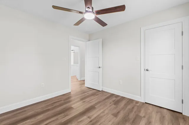 an empty room with wooden floor ceiling fan and windows