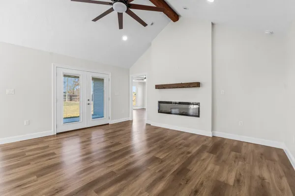 a view of an empty room with a window and wooden floor