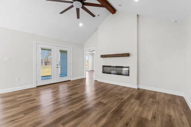 a view of an empty room with a window and wooden floor